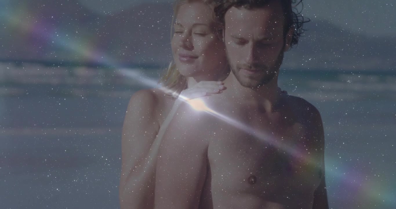 Luce solare che provoca un flare che si sposta su una coppia che indossa un bikini giallo sulla riva per una pubblicità di viaggio.