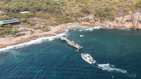 vista aérea con vistas a un barco que llega al muelle en la isla leñosa, día soleado, en el suroeste de australia - órbita, disparo de drones