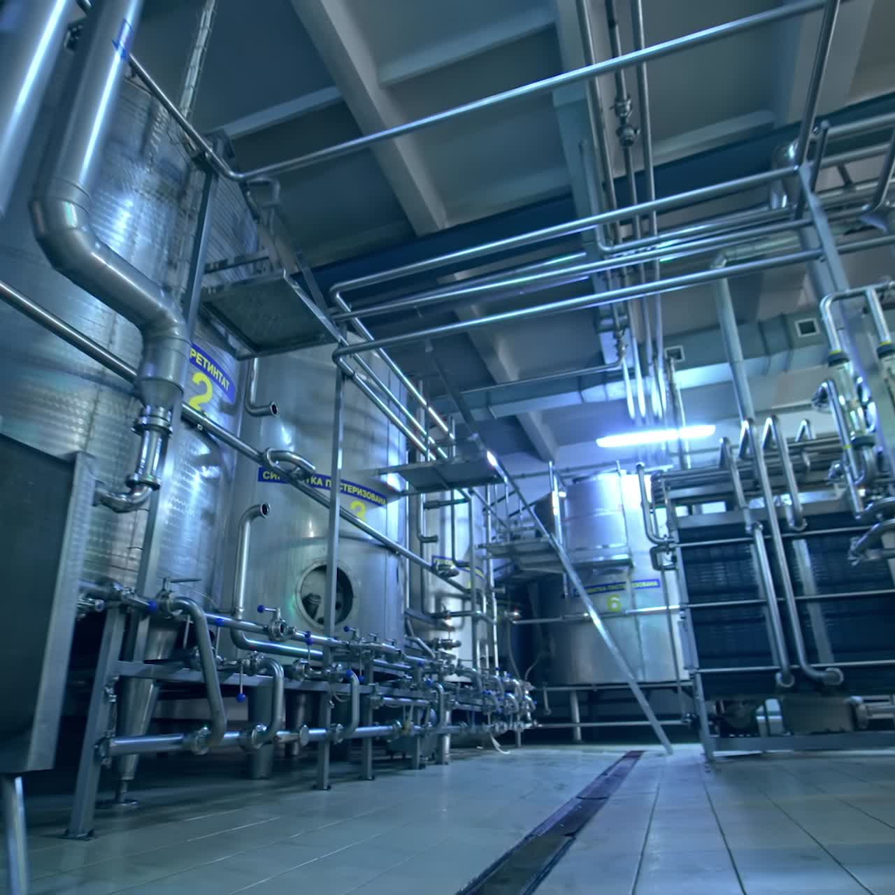 Big room in the milk manufacturing factory. Stainless steel modern equipment for dairy production. View from below