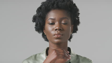 studio portrait of serious young businesswoman resting face on hand against plain background