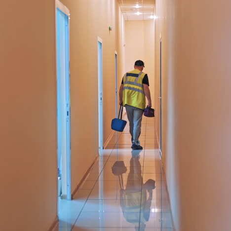 medical worker goes through the long corridor in laboratory. back view video of a male in special vest is holding bag with sample analysis in hospital.