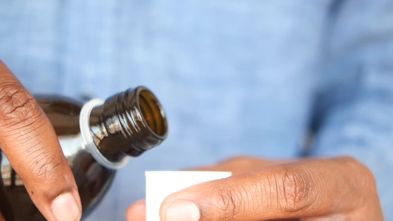una persona vertiendo medicina líquida en una taza