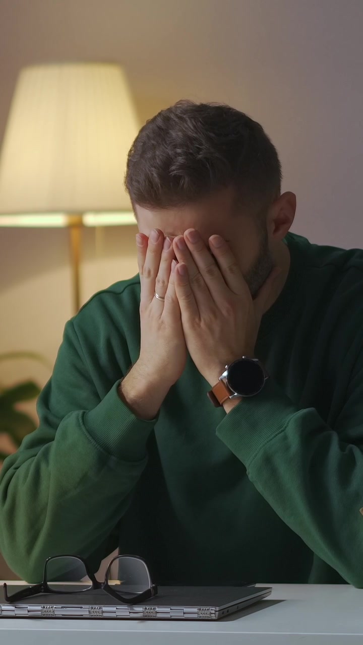 Giovane uomo stressato con mal di testa mentre lavora al laptop
