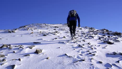 male hiker walking to the summit of the cuillin mountains on a sunny winter day in scotland