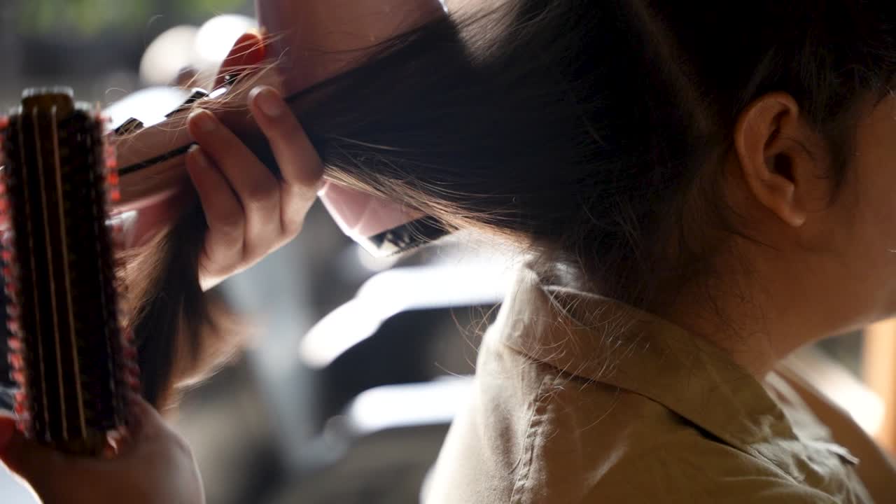 Hair stylist brushes and blow-dries a woman's hair during an outdoor grooming session