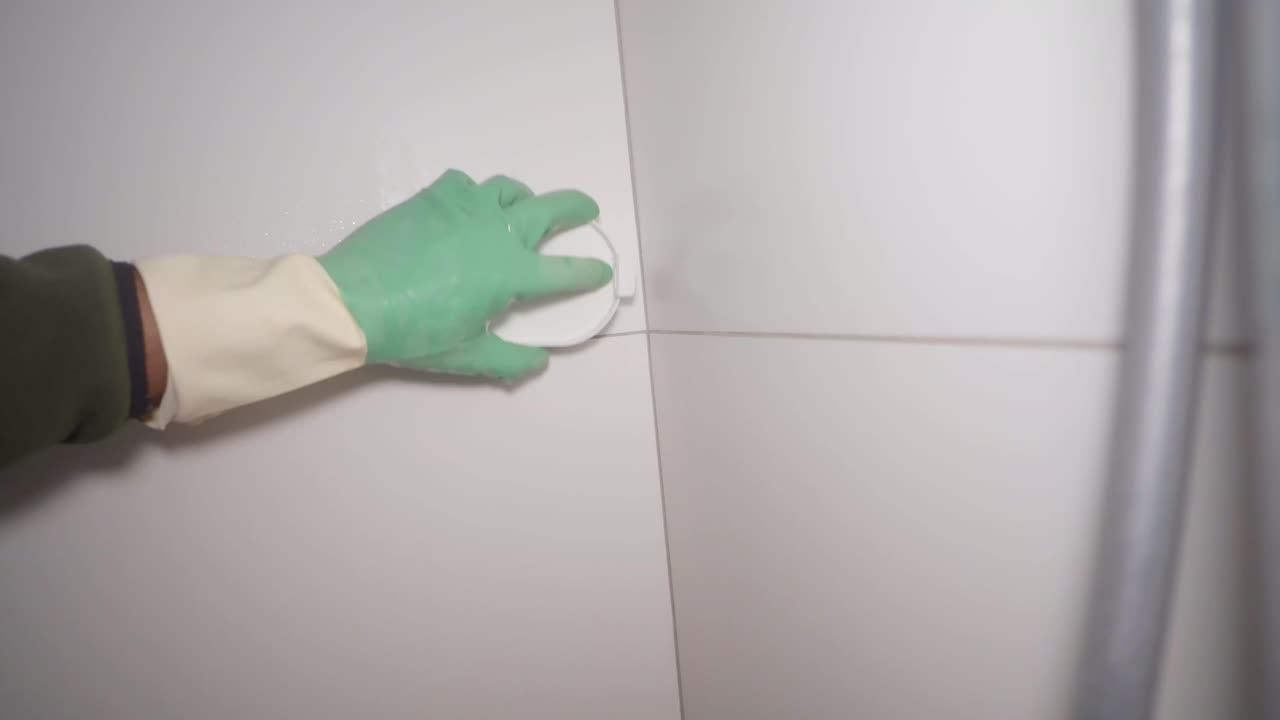 Cleaning tiles with a gloved hand