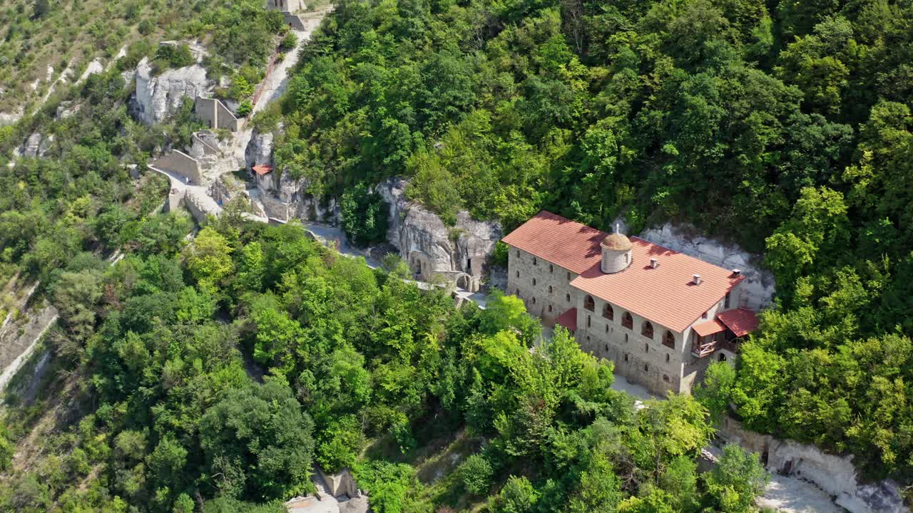Beautiful buildings in the mountains. Stone architecture on the hill among green nature in summer. Camera moving down.
