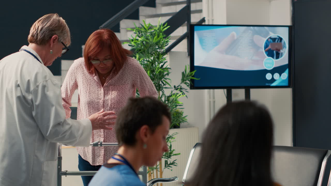 Doctor assisting senior woman with walker in hospital waiting area