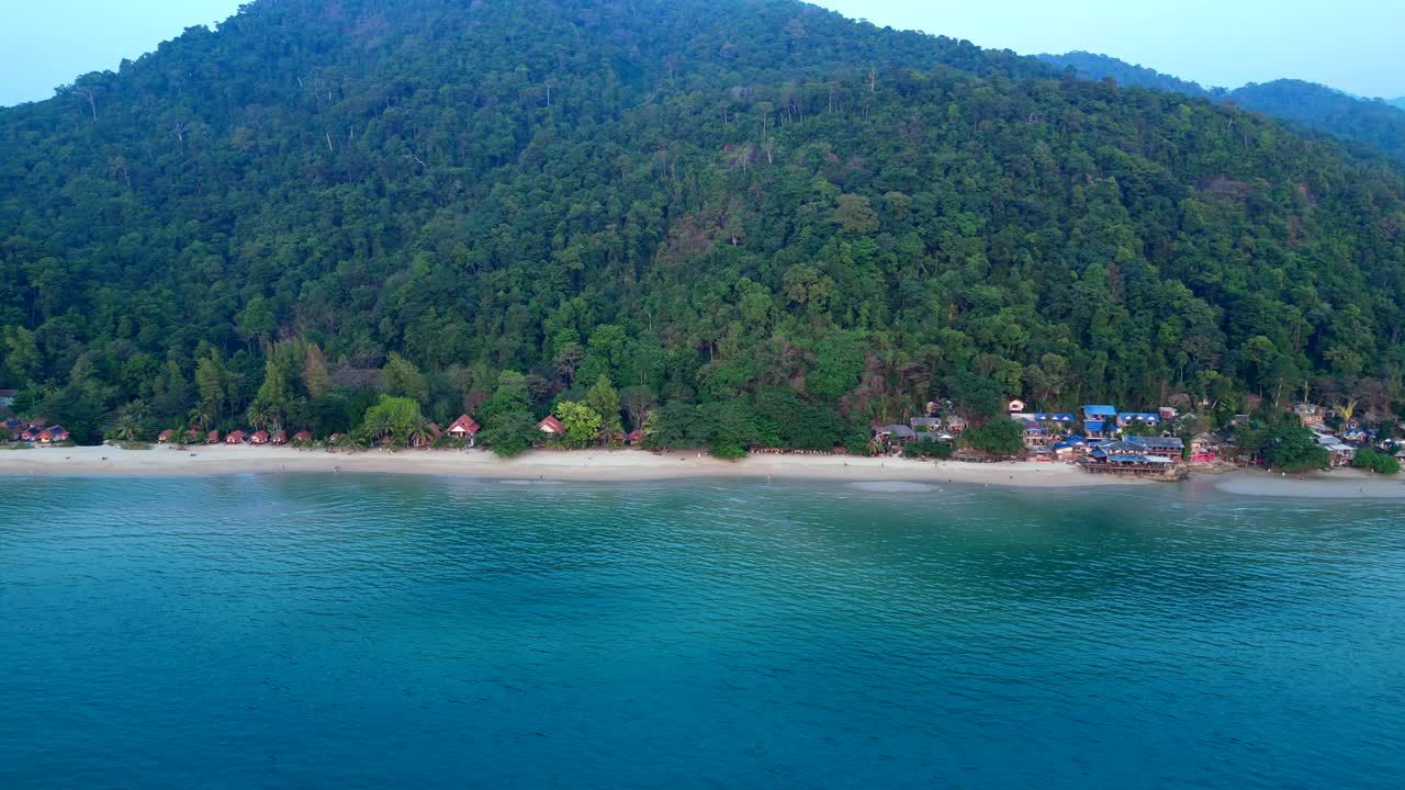 Koh Chang Tropical beach with bungalows along the shore and dense green jungle covering a mountain. Breathtaking aerial view panorama overview drone