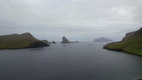 drangarnir pilas de mar, tindholmur y mykines con granja de salmón frente en el océano atlántico, islas feroe