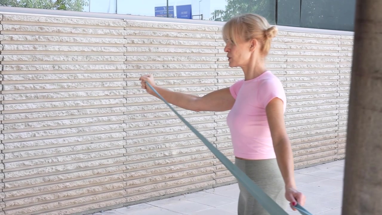 Una donna si allena all'aperto con una fascia di resistenza, concentrandosi su fitness e benessere.