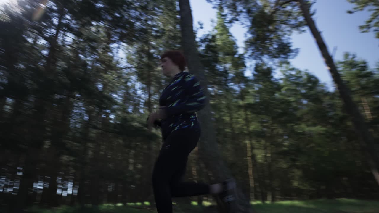 A woman in sportswear runs past the camera in the morning sunlit forest