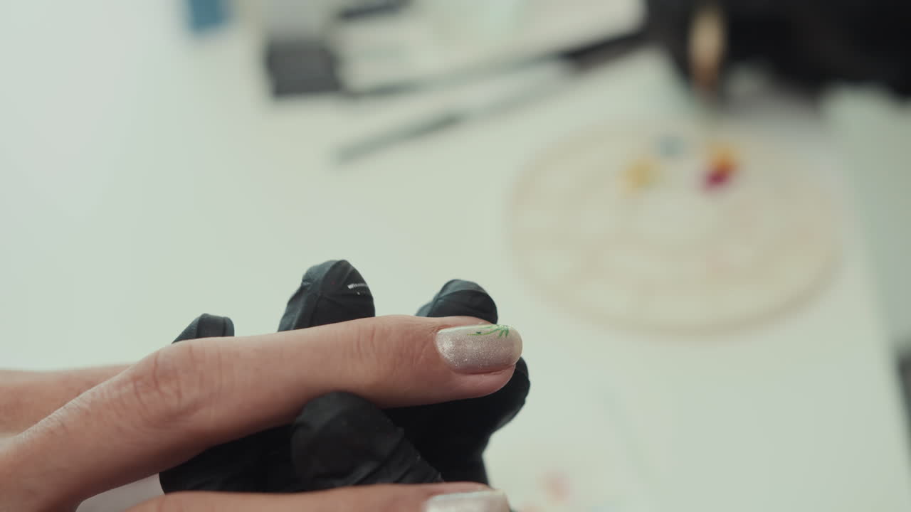 Kosmetolog tegner på negle på klient under manicure