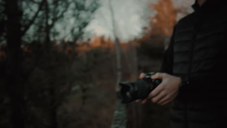 revealing a focused and handsome caucasian photographer holding a dslr or mirrorless professional camera in his hands and looking at the horizon to choose the best composition for a landscape photo