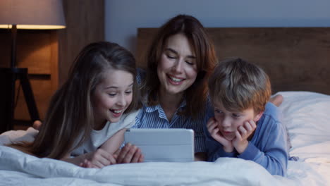 Madre-Caucásica-Y-Su-Pequeño-Hijo-E-Hija-Acostados-En-La-Cama-Y-Viendo-Algo-En-La-Tableta