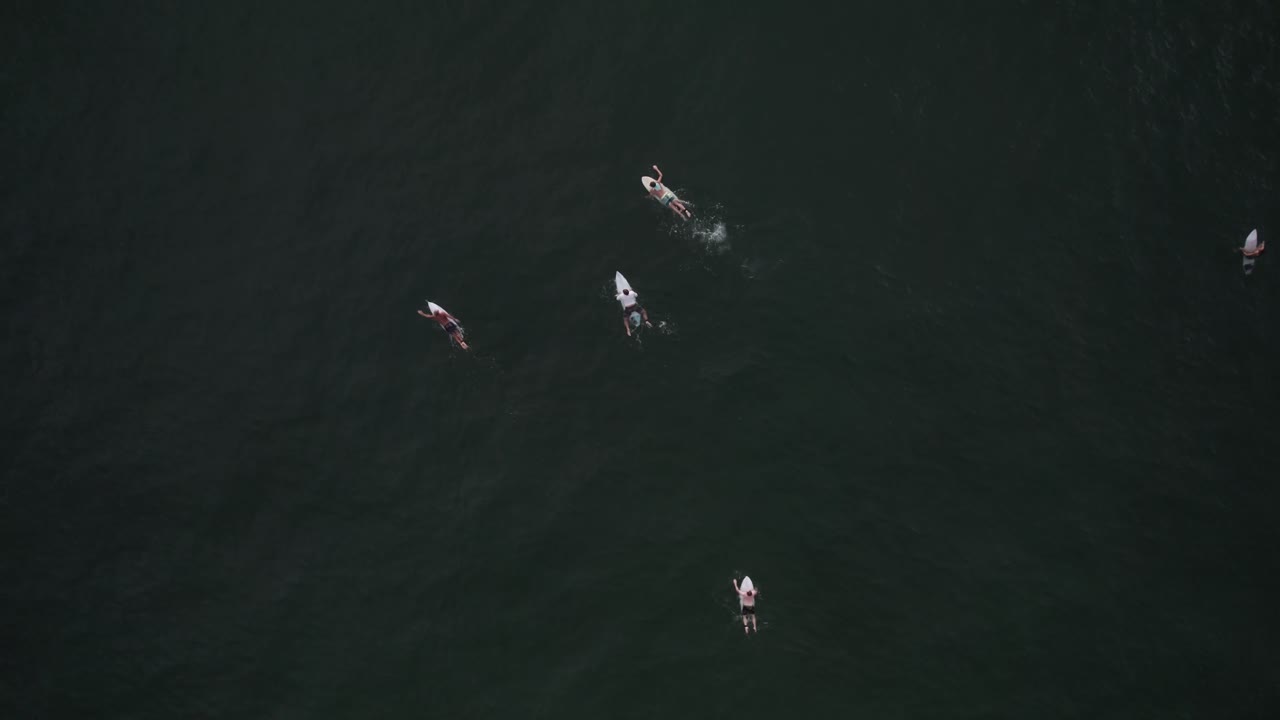 코스타리카의 산타 테레사 해변에서 파도를 향해 노를 젓는 서퍼들의 조감도