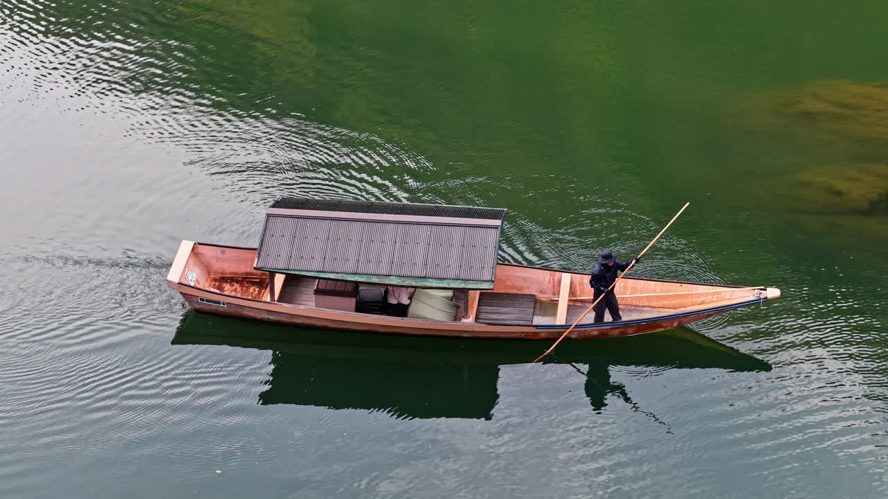 Aerial drone view of a man on a moving boat on the Katsura River in daylight