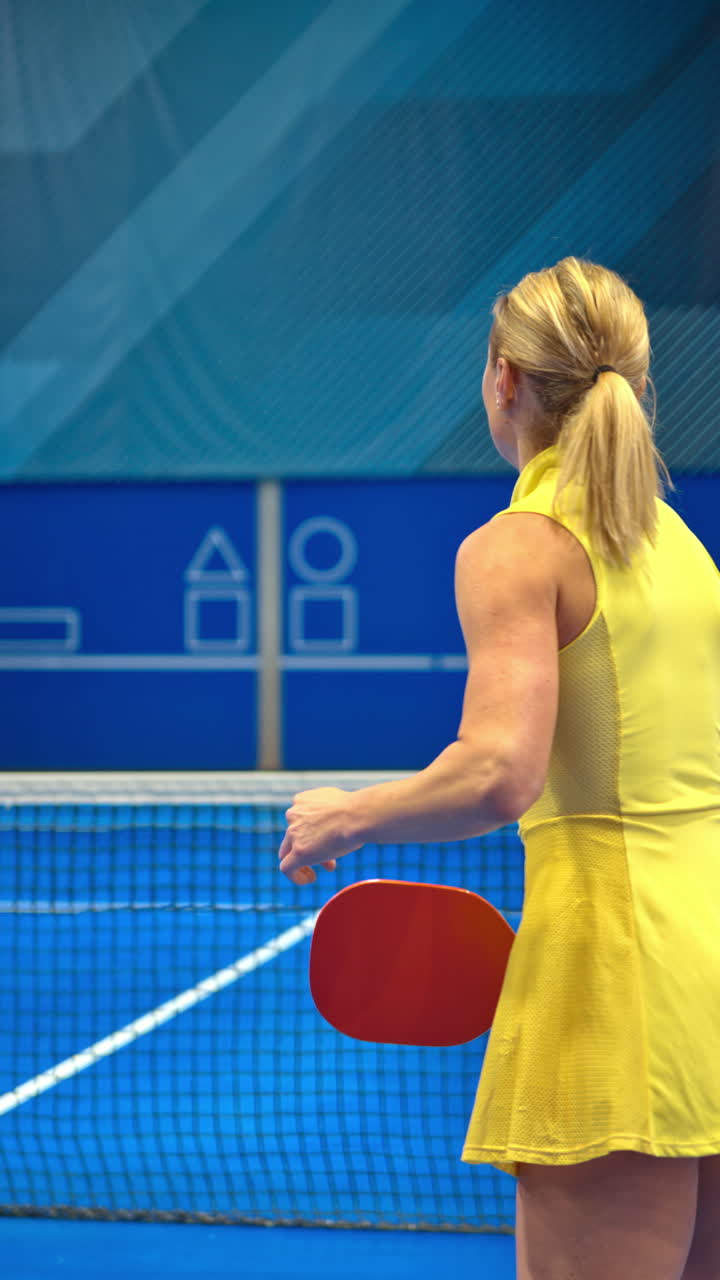 Two men and two women playing pickleball on a blue, inside court. Vertical