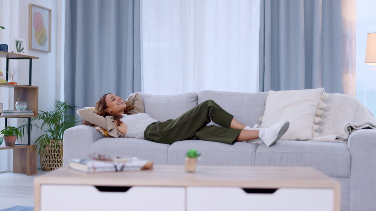집 거실의 소파에서 휴식을 취하는 미소 짓는 여자