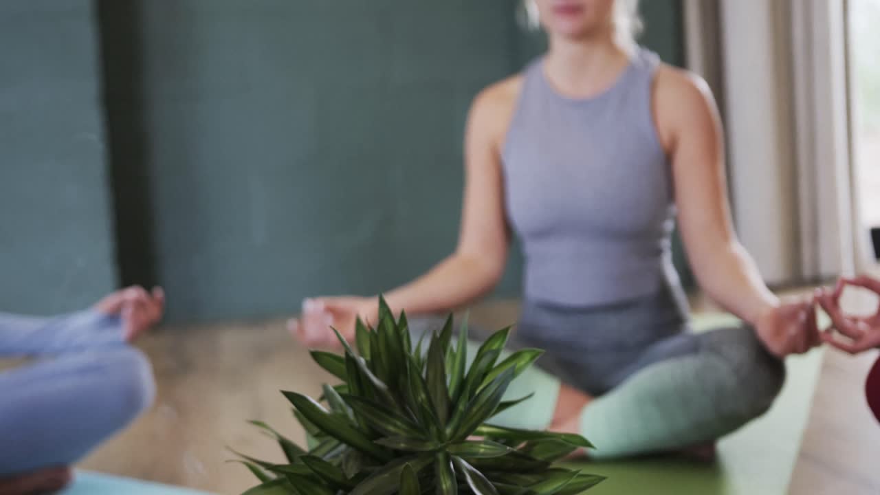 Donne diverse che praticano il mudra della pazienza e meditano insieme in uno studio di yoga
