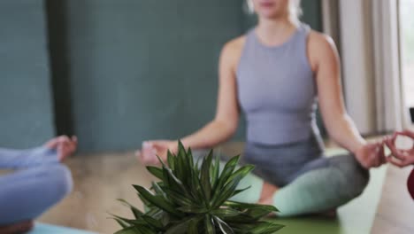 diverse women practicing patience mudra and meditating together in yoga studio