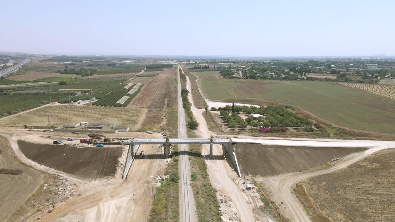 un puente sobre vías ferroviarias para pasar el transporte agrícola, en medio de campos y huertos, un puente en medio de la construcción