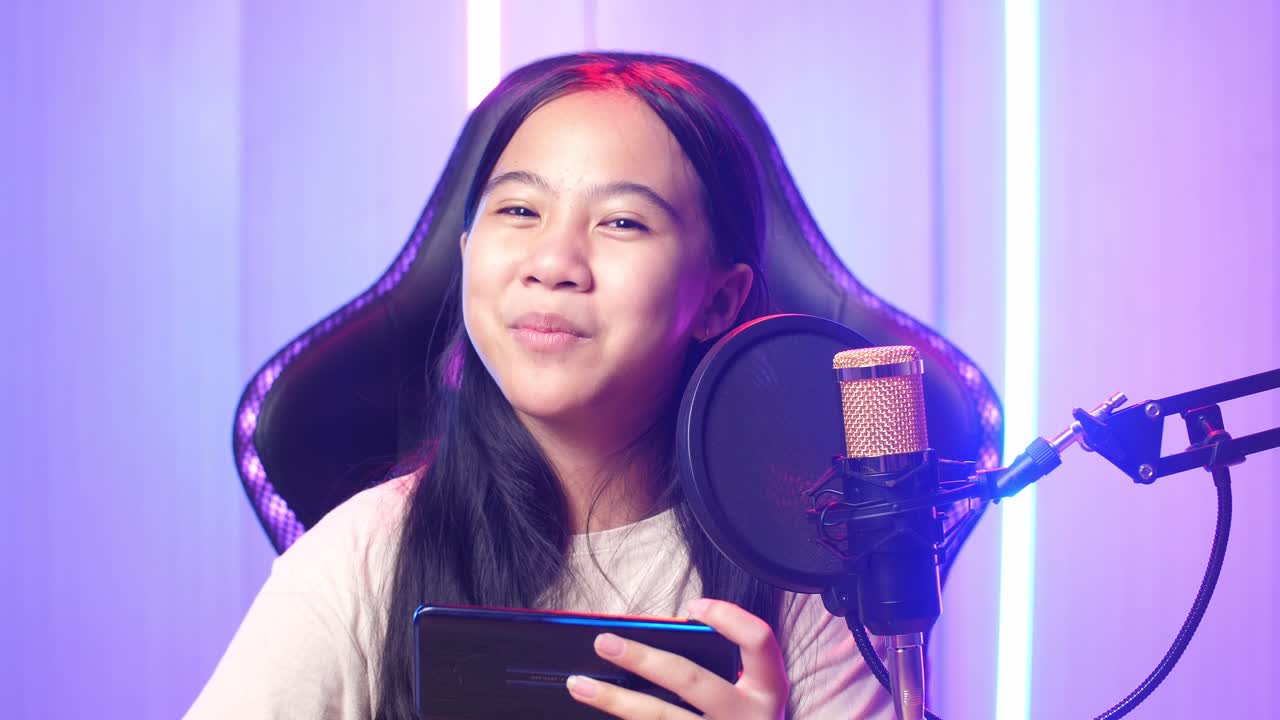 Asian Kid Girl Holding Mobile Phone And Talking To Camera While Live Stream