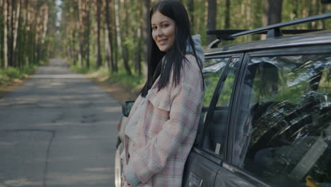 woman by a car in a forest