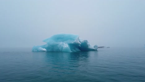 pasando un iceberg azul brillante en la laguna del glaciar jokusarlon en el sur de islandia