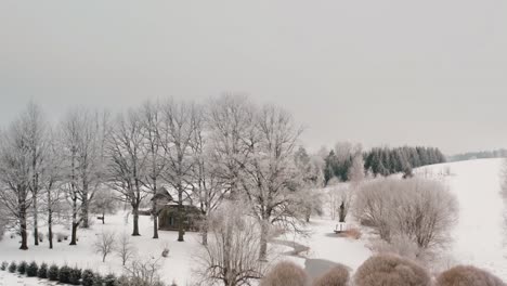 Aerial view of a family home in the countryside during the winter with lots of snow on the ground and frost in the trees. Orbiting drone shot around property in suburbs.