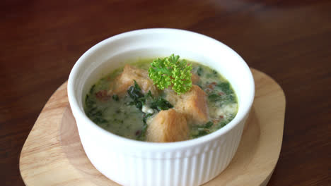 spinach soup with bread in white bowl