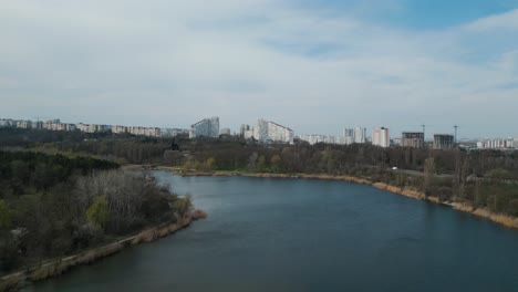 establishing drone shot of chisinau bulevardul dacia in moldova in spring with lake in the foreground - aerial 4k panorama view of the chișinău city gates