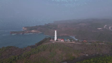 aerial birds eye view orbit shot of lighthouse at baron beach, indonesia at day