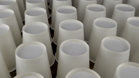 row of white disposable paper cup for coffee or hot beverage on dark backdrop rotate slowly.