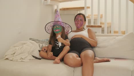 madre embarazada relajándose con su hija en disfraz de bruja