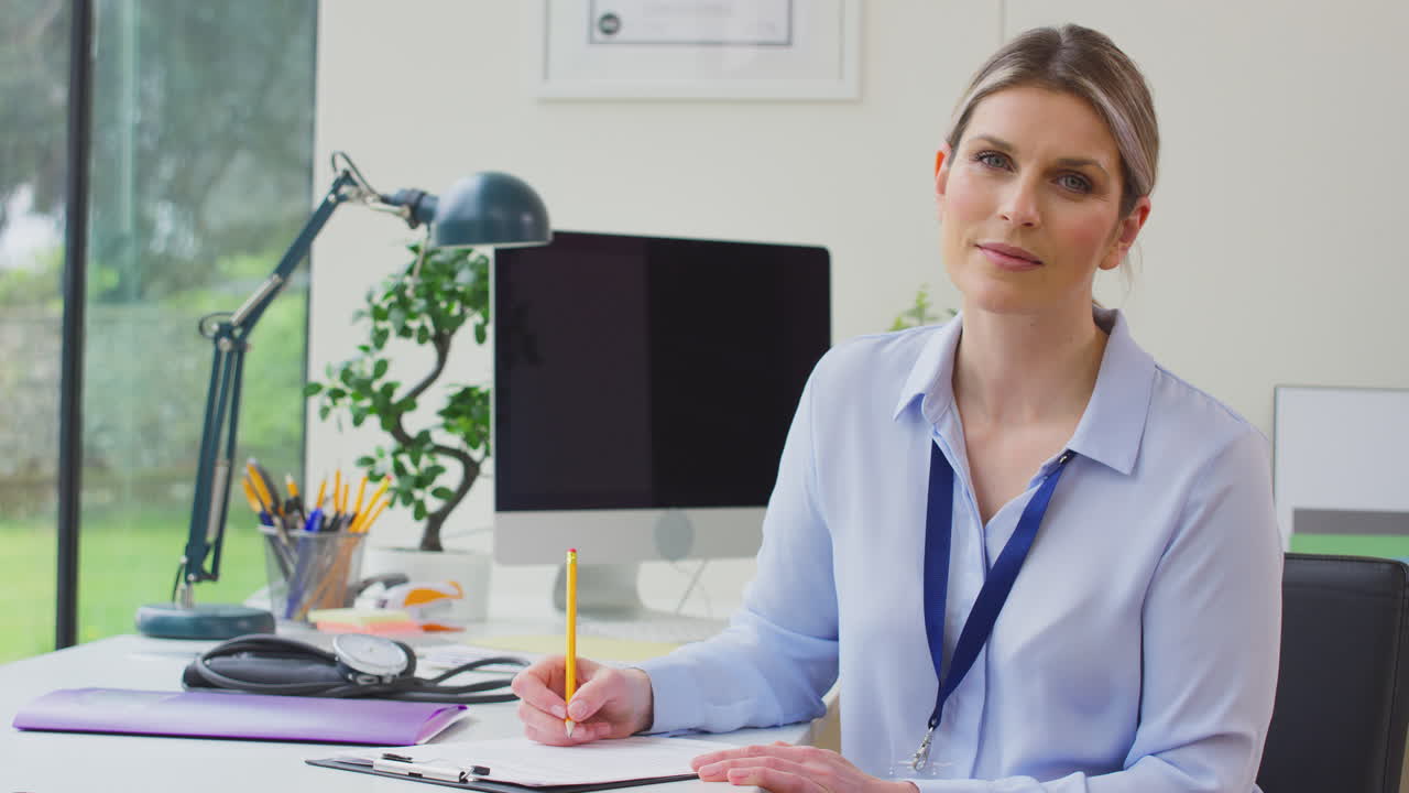 retrato de una mujer médico o médico de cabecera en la oficina sentada en el escritorio escribiendo notas en el clipboard