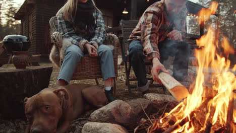 couple and dog sitting by bonfire in evening