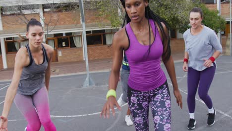 diverse female basketball team playing match, dribbling ball