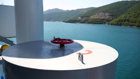 ferry sailing along the coast of greece with a red valve, part of its equipment