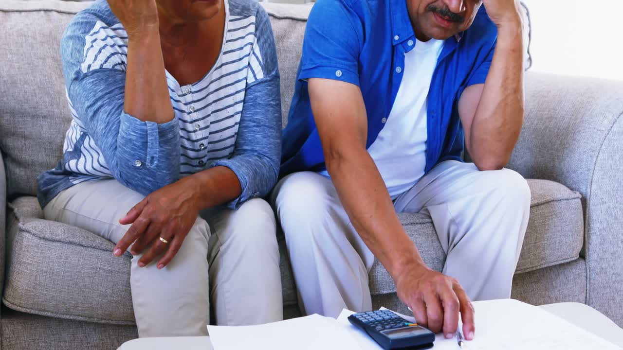 casal de idosos a calcular faturas na sala de estar 4k