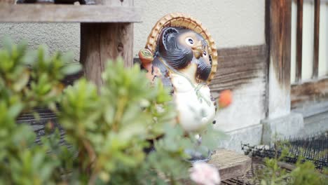 Grüne-Blätter,-Tanuki,-Waschbärstatue-Sittng-Vor-Einem-Haus-In-Kyoto,-Japan-Sanfte-Beleuchtung-Zeitlupe-4k