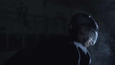 Camera-Round-Shot-Of-A-Concentrated-Male-Hockey-Player-Getting-Ready-To-Play-On-A-Dark-Ice-Arena