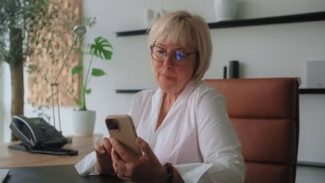 senior woman using smartphone in office
