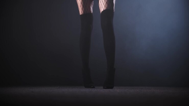 Sexy woman with long legs dancing in the dark smoky studio
