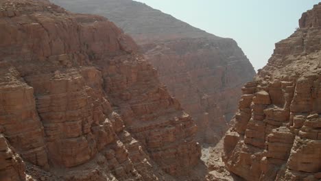 Bird's-eye-view-from-drone-going-through-rocky-valleys-in-desert-mountains,-United-Arab-Emirates