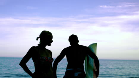 Surfer-kissing-his-girlfriend-on-the-beach-and-running-to-the-sea