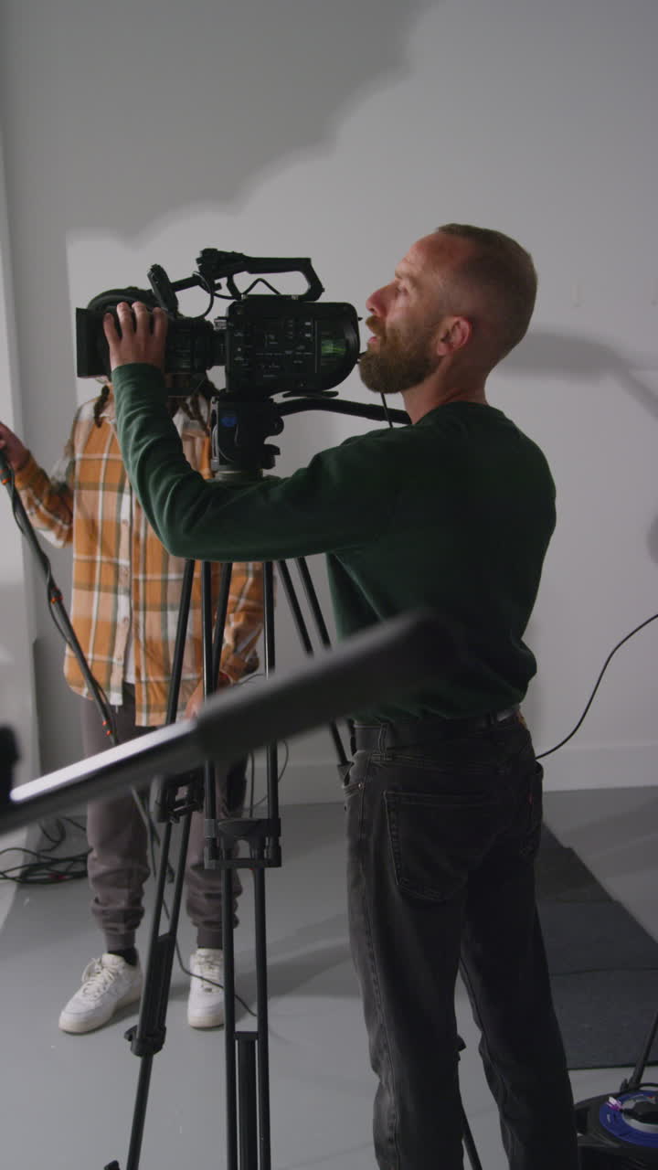 Vertical Video Of Male Sound Recordist And Camera Operator Working On Film Set Shooting Movie Or Video In Studio