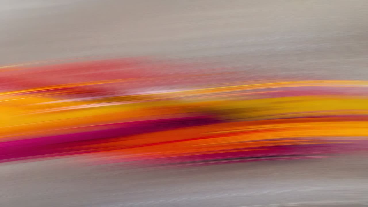 Panning camera capturing colorful horizontal streak sliding on gray backdrop, showing blur