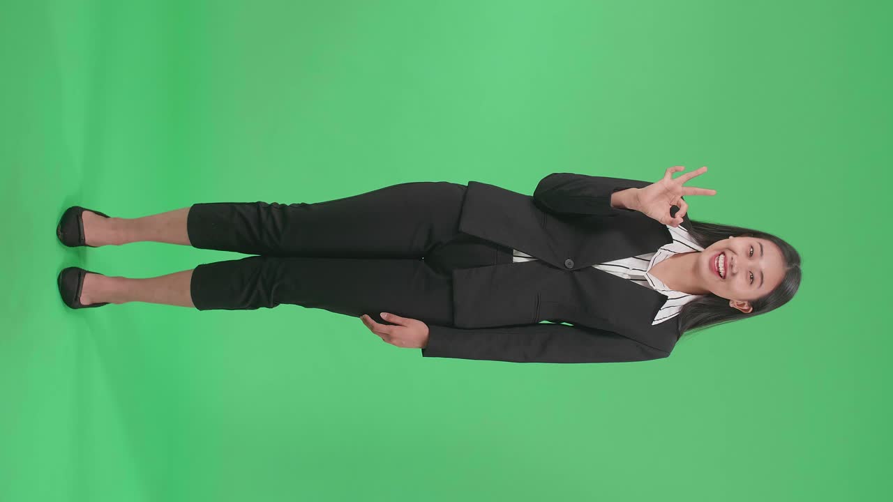 Full Body Of An Happy Asian Woman Showing Okay Gesture To The Camera In The Green Screen Studio