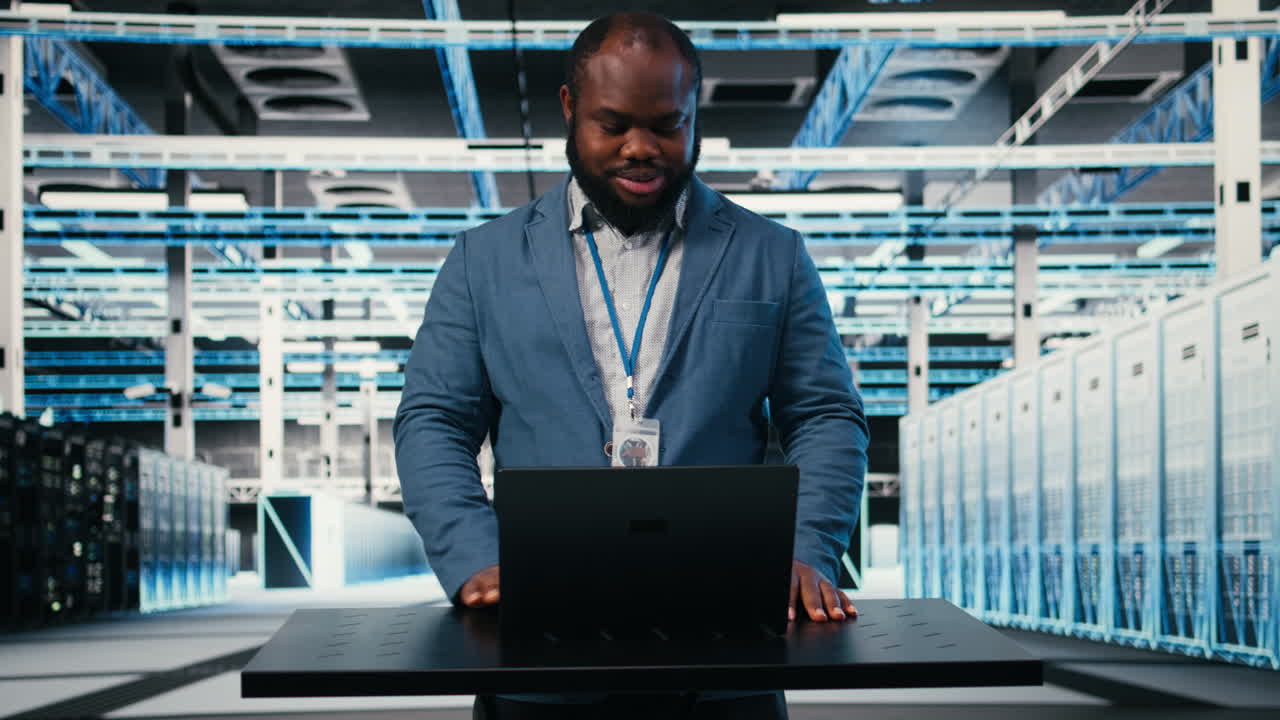Uomo afroamericano che lavora al laptop in un data center moderno
